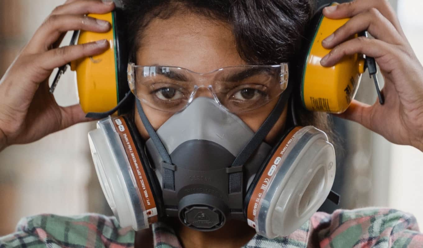 a person wearing a gas mask holding headphones close to ears